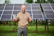 © anatoliy_gleb - Successful investor happy about his profit. Male adult showing thumbs up and smiling straight to camera on background of solar panels.