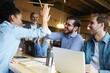 © opolja - Successful business people giving each other a high five in a meeting. Two young business professionals celebrating teamwork in an office