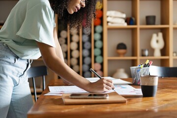 Wall Mural - Young designer work project. Photo woman working with new startup project in modern loft. Generic design notebook on wood table