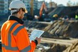 © Chand Abdurrafy - A Caucasian male land development manager using a tablet to coordinate and manage construction activities on a development project