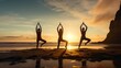 Silhouettes of three female standing in yoga pose on beach at sunrise. Group of people practicing healthy lifestyle.