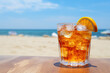 © Firn - Cocktail with ice cubes and lemon slice with beach in background with copy space