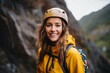 Smiling woman hiker in yellow jacket and helmet looking at camera