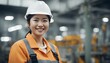 Portrait of a happy female asian factory worker wearing hard hat and work clothes