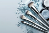 Silver make-up brushes and crushed silver eyeshadow on a light background