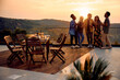 © Drazen - Cheerful friends have fun while drinking wine and talking on terrace at sunset.