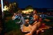 © Drazen - Happy couple enjoying in movie night with friends in backyard.