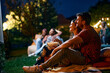 © Drazen - Happy couple relaxing during movie night with friends in backyard.
