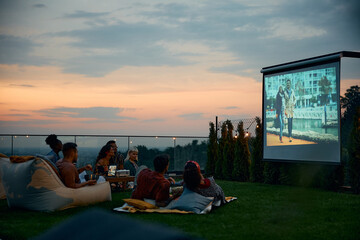 Group of friends enjoying in movie night on patio.