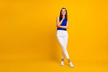 Full length photo of good mood thoughtful lady dressed blue top arm chin looking empty space isolated yellow color background