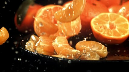 Wall Mural - Tangerine slices fall into a wet plate with splashes. Filmed on a high-speed camera at 1000 fps. High quality FullHD footage