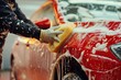 Worker cleaning red car on a car wash