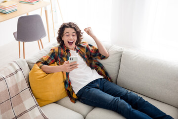 Sticker - Photo of cheerful lucky guy wear plaid shirt lying sofa winning gale modern gadget indoors room home house