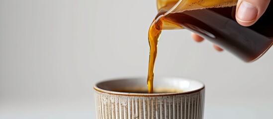 Sticker - A hand pours coffee into a cup on a white background, captured in a close-up image.