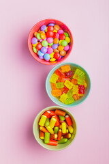 Colorful sweet jelly candies in bowl on pink background. Top view.