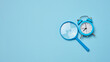 Alarm clock and magnifying glass on a blue background, symbolizing the concept of a deadline