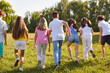 © Studio Romantic - Group of a kids friends playing outside in the park standing back and running in nature. Happy children playing games and having fun outdoor on a sunny summer day in casual clothes.