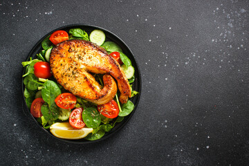 Wall Mural - Salmon salad with fresh steak and vegetables on black background. Keto diet, healthy food. Top view copy space.