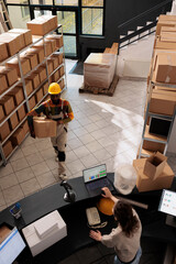 Wall Mural - Top view of diverse employee working at products delivery in warehouse, preparing customers orders. Stockroom workers working at merchandise quality control at counter desk in storehouse