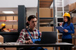 © DC Studio - Young asian warehouse employee working on laptop in post office storage room. Delivery service worker analyzing customer orders checklist on computer and managing dispatching