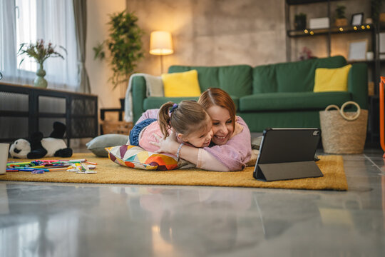 Mother and daughter use digital tablet to watch online video at home