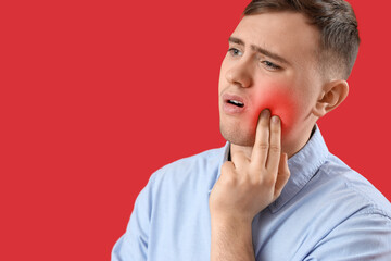 Wall Mural - Young man having toothache on red background