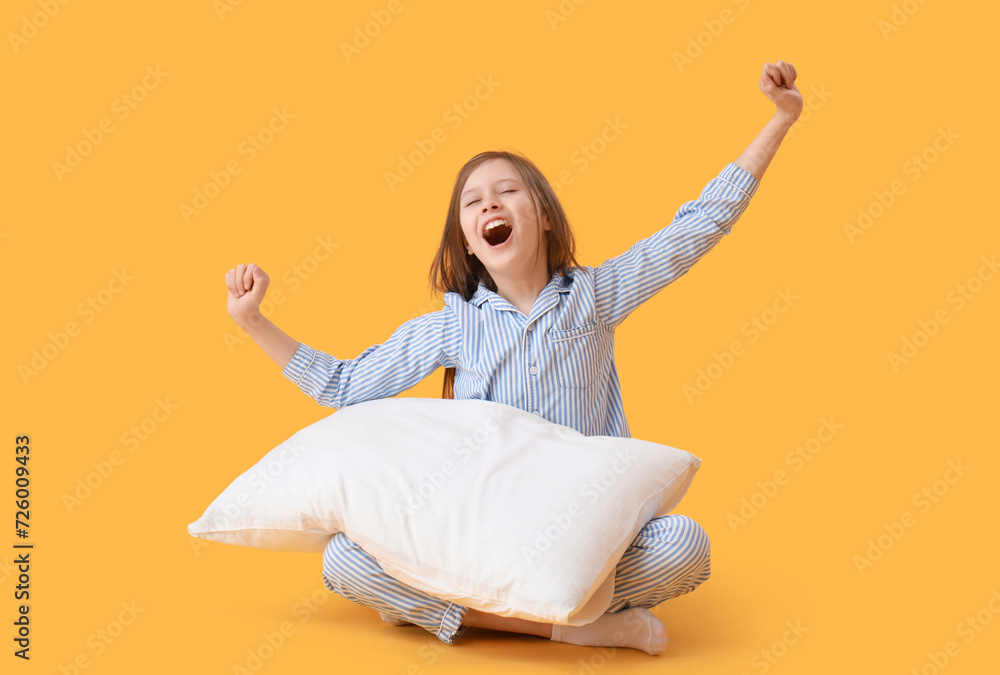 Sleepy little girl with pillow on yellow background