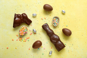 Chocolate Easter eggs with sprinkles and bunnies on yellow background