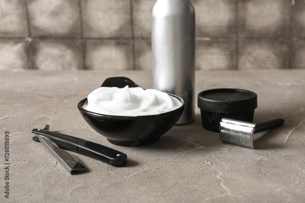 Set of shaving accessories on grunge grey table near tile wall