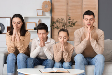 Canvas Print - Family praying together on sofa at home