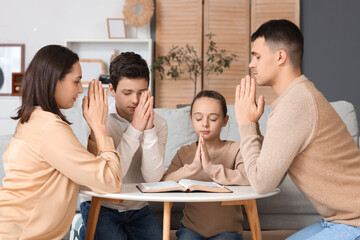 Canvas Print - Family praying with Holy Bible on table at home