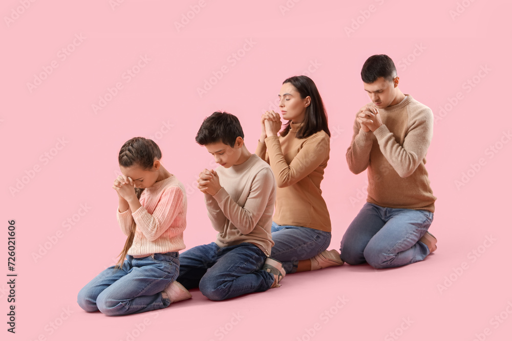 Family praying together on pink background