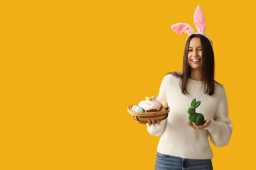 Sticker - Pretty young woman with bunny ears, toy rabbit and Easter basket on yellow background