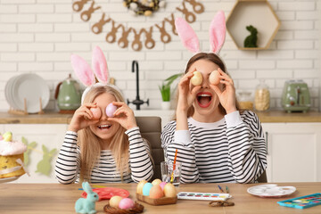 Poster - Cute little girl and her mother with painted Easter eggs in kitchen