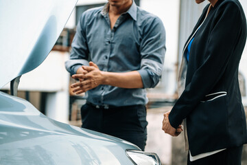 Man help woman fix the car problem. He pop up the car hood to repair the damaged part. uds