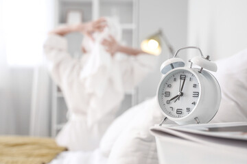 Wall Mural - Alarm clock on table of woman after shower in bedroom, closeup
