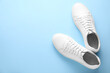 canvas print picture - Pair of stylish white sneakers on light blue background, top view. Space for text