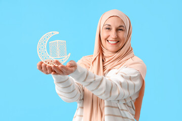 Poster - Mature Muslim woman with crescent on blue background. Ramadan celebration