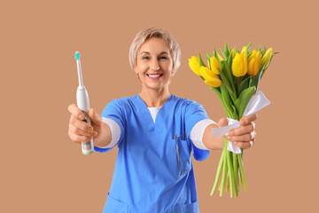 Canvas Print - Mature female dentist with tulips and electric toothbrush on brown background. International Women's Day celebration