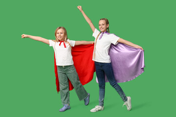 Cute teenage girls dressed as superheroes on green background