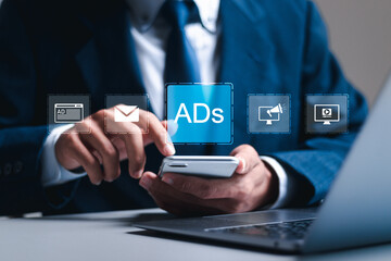Wall Mural - digital marketing concept, businessman using smartphone and laptop with virtual ads icon for digital