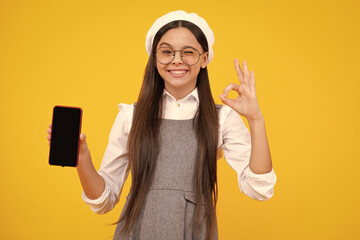 Poster - Happy face, positive and smiling child girl 12, 13, 14 years old with smart phone. Hipster teen girl types text message on cellphone, mobile app. Kid showing blank screen mobile phone, mockup.