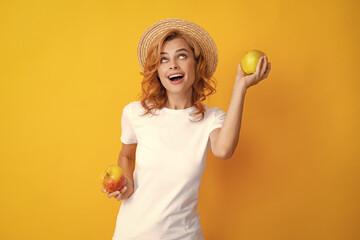 Wall Mural - Portrait of a smiling happy girl with apple isolated over yellow background.