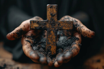 Dirty male hands holding a wooden cross on a black background