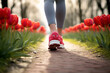 Close up of woman's feet with sport shoes jogging in park with red tulip spring flowers