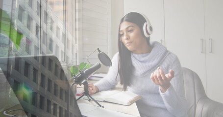 Wall Mural - Image of biracial businesswoman recording podcast over people walking and cityscape