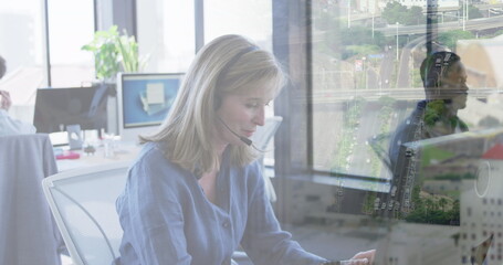 Wall Mural - Image of diverse business people in office over cityscape