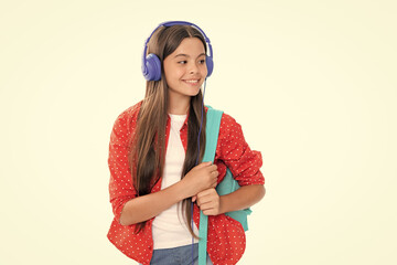 Poster - Back to school. Schoolgirl student in headphones with school bag backpack on isolated studio background. School and education concept. Portrait of happy smiling teenage child girl.