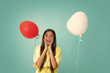 Poster - Valentines day and kids concept. Teenage girl in yellow dress with red heart-shaped balloon over blue background. Surprised face, surprise emotions of teenager girl.