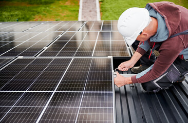 Wall Mural - Man worker mounting photovoltaic solar panels on roof of house. Engineer in helmet installing solar module system with help of hex key. Concept of alternative, renewable energy.